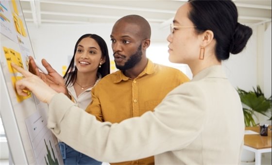 Photo of three people looking at chart paper.