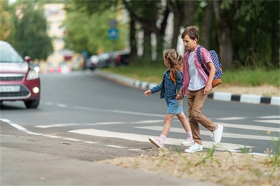 Photo of kids crossing sidewalk of street. 
