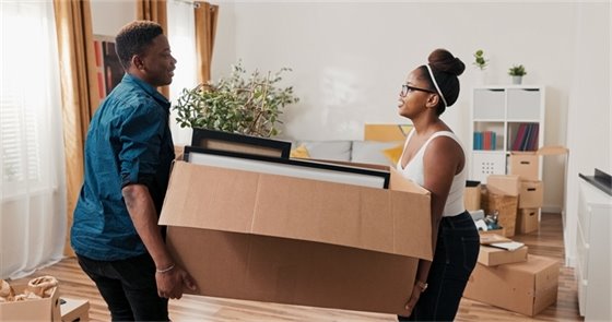 Man and woman lifting a moving box in their apartment. 